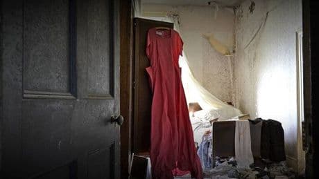 Abandoned eerie Red Dress Manor with love letters strewn on floor and clothes hanging in wardrobes