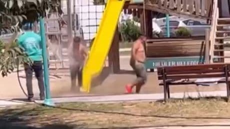 Temizlik personeli, parktaki çocukları hortumla su sıkarak serinletti