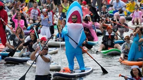 Photos show costumed participants steer stand-up paddle boards at a festival in Russia