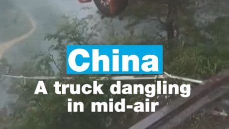 China: Truck with driver inside dangling in mid-air