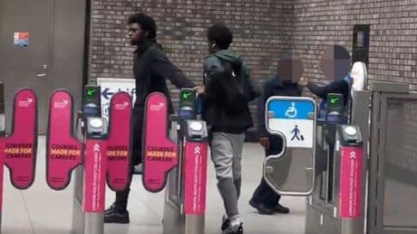 Fare dodgers push their way through barriers in front staff