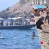 KIJK. Badgasten proberen migranten te vangen die met bootje aankomen op druk Spaans strand