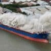 Plume of smoke across city as ship on fire in dock