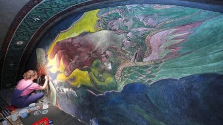 Inside a historic church painted with murals that reflect searing social commentary