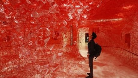 La japonesa Chiharu Shiota invita a adentrarse en su casa edificada con telarañas rojas en el Azkuna Zentroa