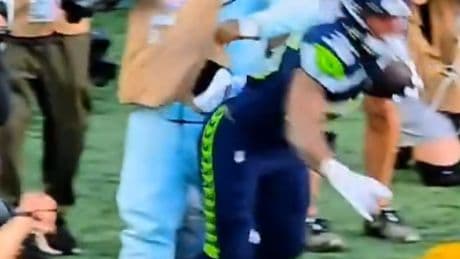 Marshawn Lynch stiff arms player to protect his camera during Seahawks preseason game in wild scene