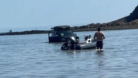 Car stranded in the sea on busy Bank Holiday at Oxwich Bay in Wales