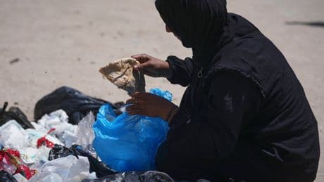 A family digs through trash for bits of food, showing Gaza's growing desperation