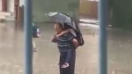 Yağmurda, sırtında torunu! İstiklal Marşı okudu