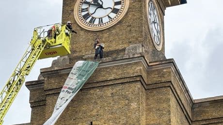 Protester carrying dog scales clock tower at King’s Cross station