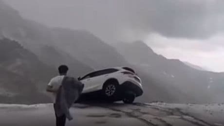 Terrifying moment car dangles precariously over sheer cliff drop sparking frantic mission to save occupants inside
