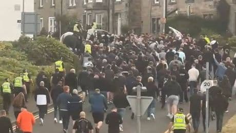Hundreds of Scots football fans in black escorted to powderkeg fixture by cops