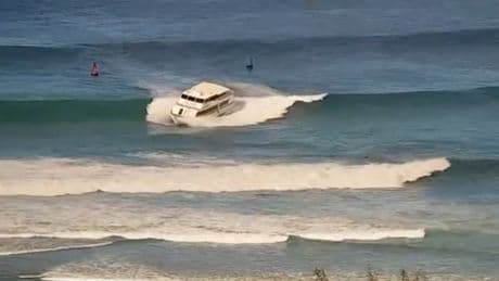Yacht-sized passenger boat runs aground in high surf off Hawaii beach