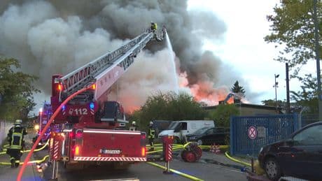 Feuerwehr warnt vor Brandgasen - Hunderte Schrott-Autos stehen in Flammen