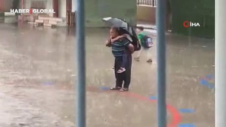 Dede torununu sırtına alarak yağmur altında İstiklal Marşı okudu