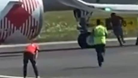 Chilling moment man ran past Milan airport staff before throwing himself into engine