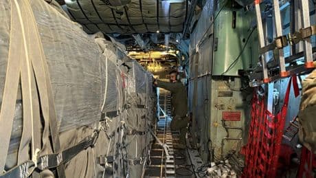 A bord d'un C-130 jordanien, des militaires larguent des colis d'aide humanitaire sur les ruines de Gaza