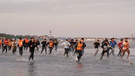 Migrants run across beach to board dinghy in the Channel