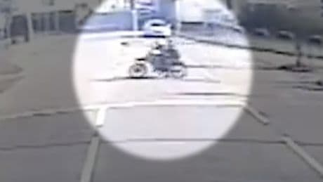 Shocking moment biker yob drags hero cop down road after fleeing during arrest for doing wheelies in town-centre
