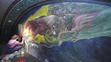 Inside a historic church painted with murals that reflect searing social commentary