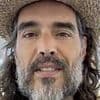 Russell Brand says he 'welcomes' rape trial 'because I know I'm innocent' as he touches down in UK for first hearing after first class flight from US