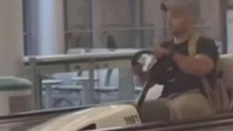Drunk man drives golf cart onto travelator as airport workers beg him to stop