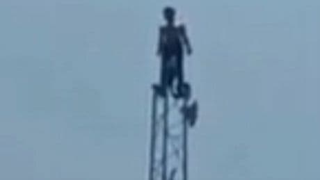 Terrifying moment man 'high on glue' scales 80-foot phone mast disrupting traffic in India
