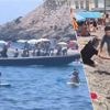 KIJK. Badgasten proberen migranten te vangen die met bootje aankomen op druk Spaans strand