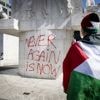 Betoger spuit leus op Nationaal Monument op de Dam tijdens demonstratie