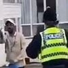 Moment asylum seeker gives the finger to protesters outside migrant hotel before being ushered away by police