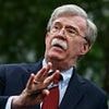 John Bolton smirks and waves upon return home to ashen-faced wife as Trump denies ordering surprise FBI raid on his ex-adviser