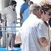 Sir Elton John is assisted off a boat in Italy before enjoying Al fresco meal with husband David Furnish after seemingly picking a side in Beckham family feud