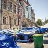 Inside Paris's latest migrant camp: Families sleep on the floor beneath tarpaulin sheets outside French capital's city hall as they wait to be given housing