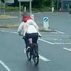 Shocking moment man cycles with child on his back merely gripping his neck - before biking the WRONG way through roundabout